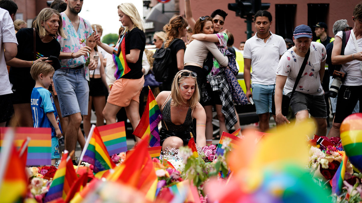 Människor lägger blommor på platsen där två personer dödades och ett 20-tal skadades i en skjutning i Oslo.