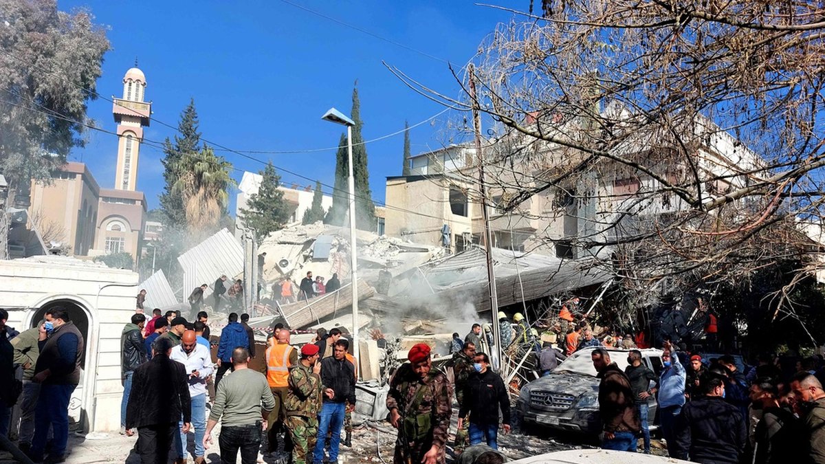 Människor samlas framför den förstörda byggnaden i Damaskus.