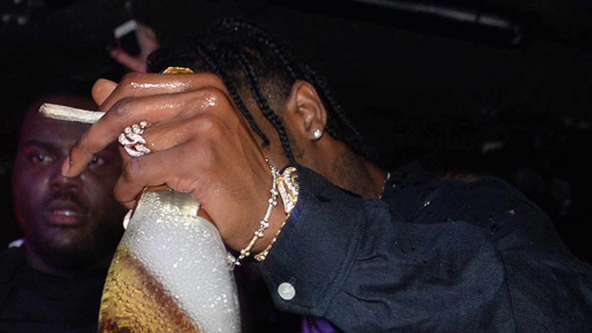 Rihannas pojkvän Travis Scott röker en joint och dricker skumpa när han spelar på Titty Twister i Paris.