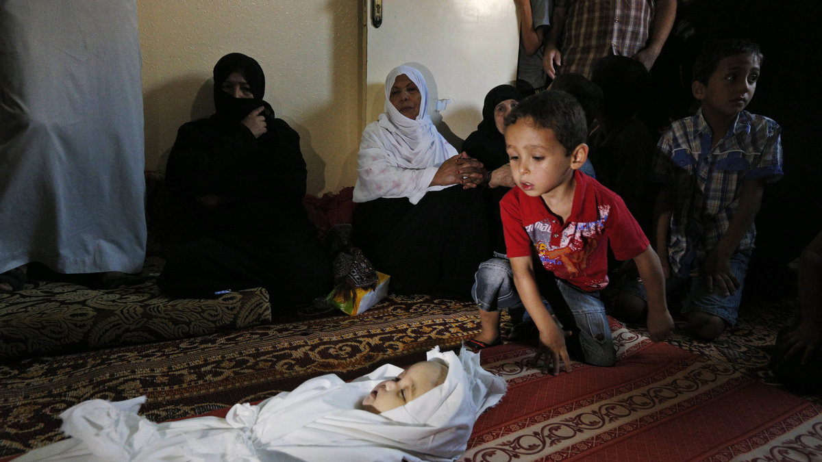 En liten pojke försöker ta in synen av ett fem månader gammalt barn som dött efter en israelisk attack. 