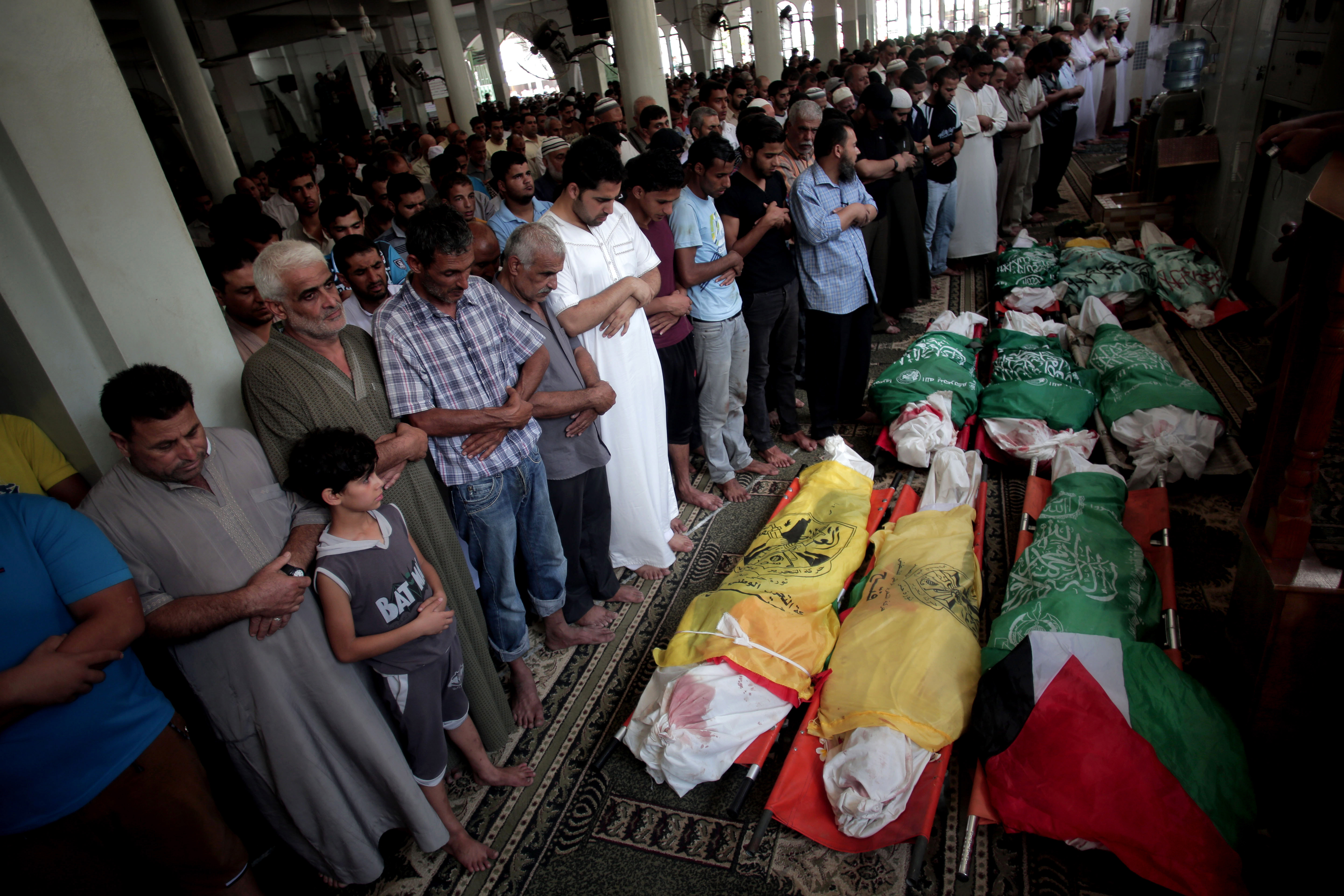 Människor ber för nio barn som omkommit efter israeliska bombningar. 