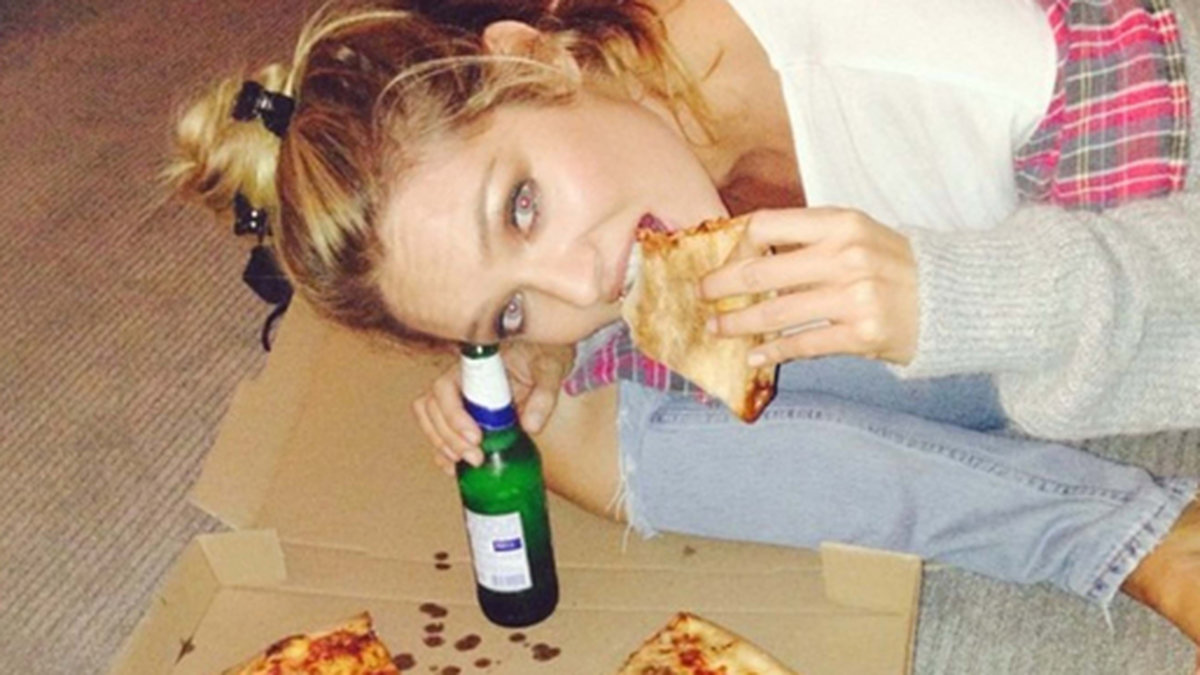 Supernodellen Candice Swanepoel äter en pizzalslice. 