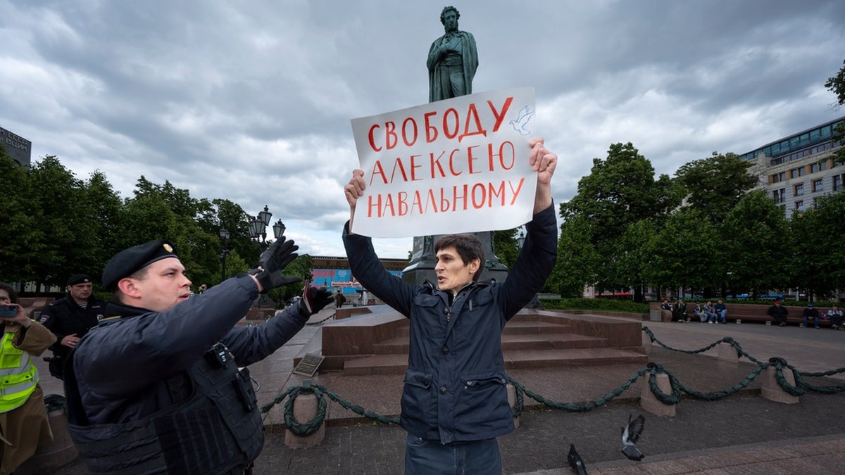 En polis griper en demonstrant i Moskva med en skylt vars text lyder 'Frihet för Alexej Navalnyj'.