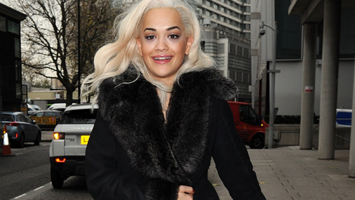 Rita Ora värmer sig med en svart päls i London.