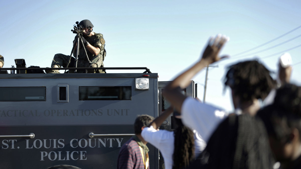 Här siktar polisen sitt vapen mot den då lugna folkmassan. I bildspelet finns fler skakande bilder från Ferguson.