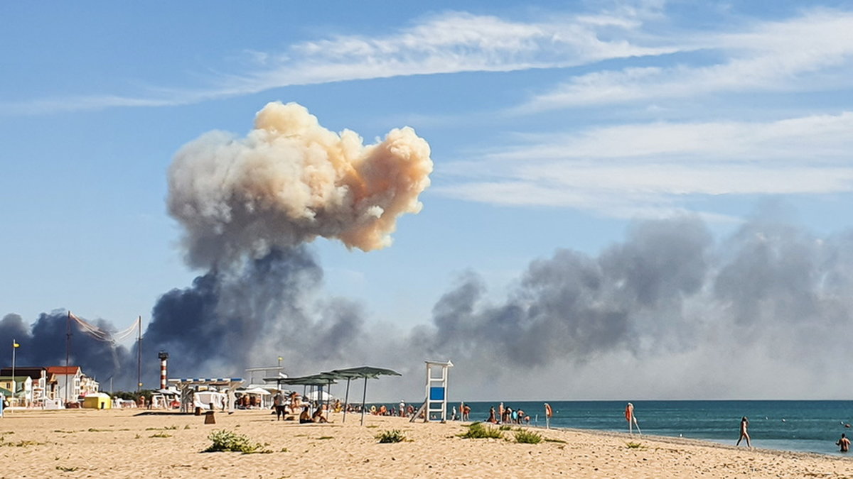Rökmoln syns från en strand i närheten efter explosionerna vid en rysk militärbas på den ockuperade Krimhalvön.