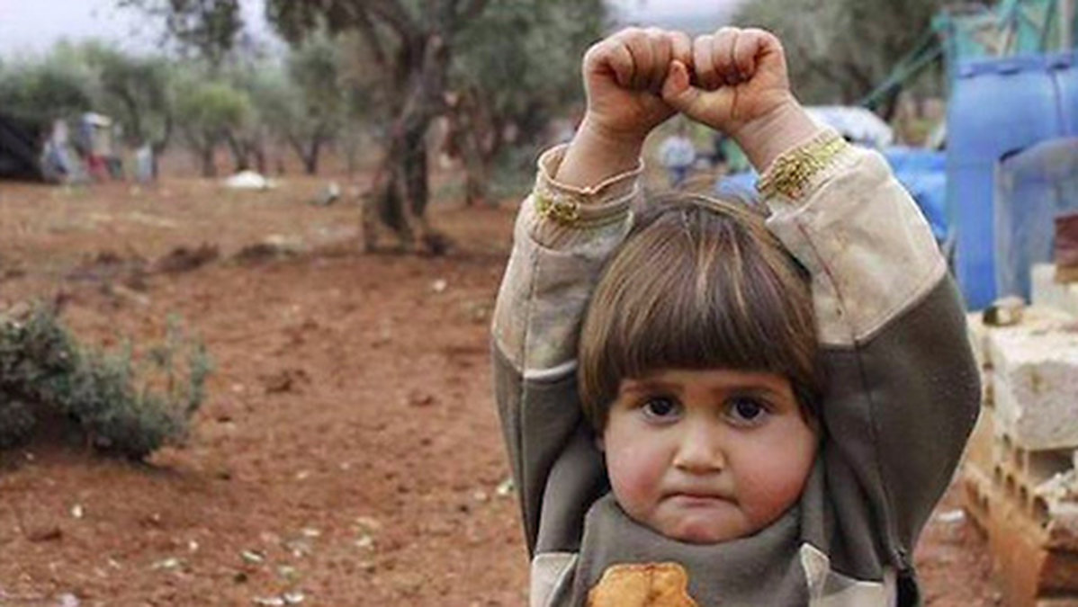 Nyheter24 har tidigare rapporterat om bilden på fyraåriga Hudea som misstog en kamera för ett vapen, och sätter händerna i luften. 