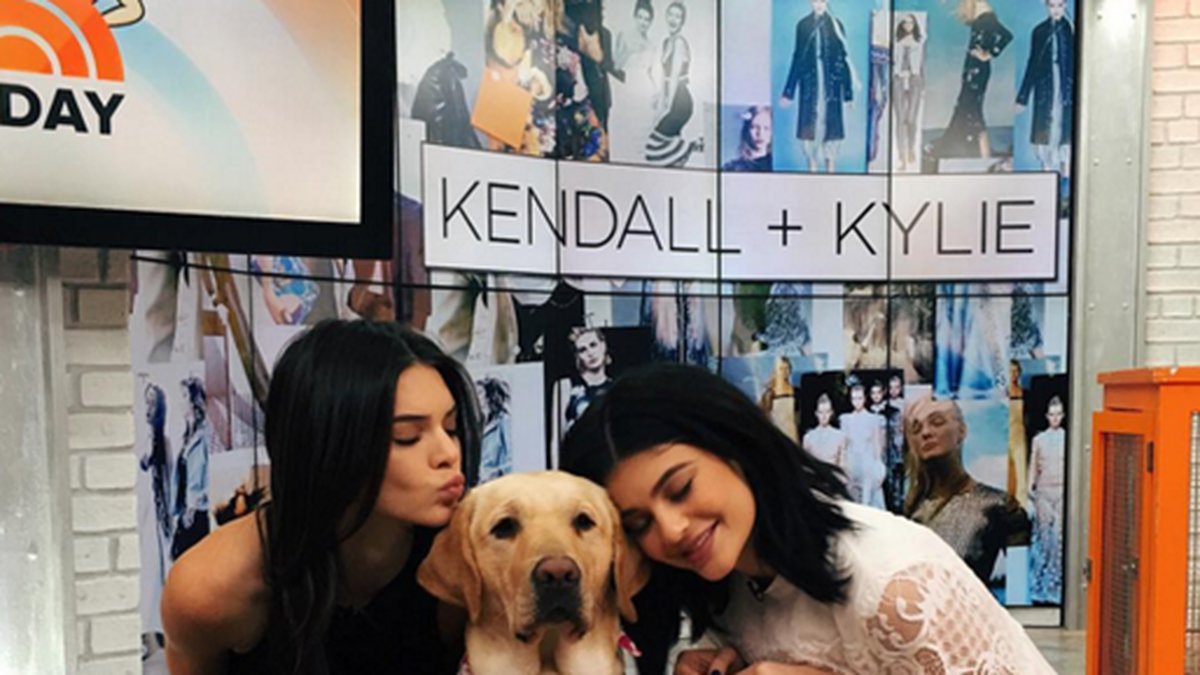 Kendall och Kylie gosar med en hund. 