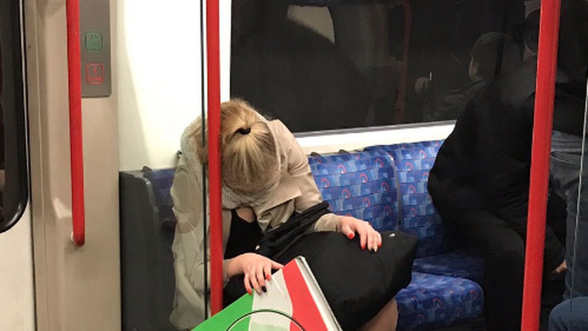 En kvinna har somnat på tunnelbanan och ner glider hennes pizza. 