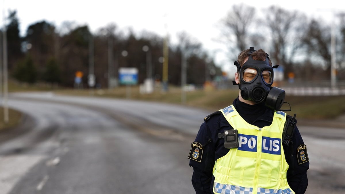 En polis i gasmask vid avspärrningen vid Säpo i februari.