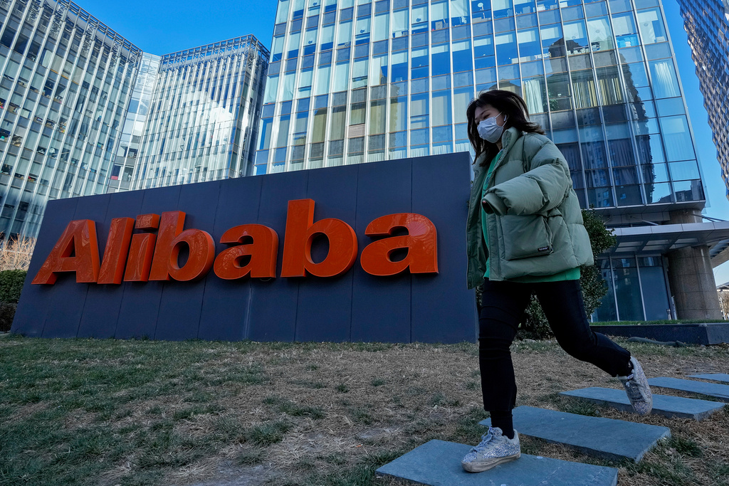En kvinna i munskydd framför Alibabas lokaler i Peking. Arkivbild.