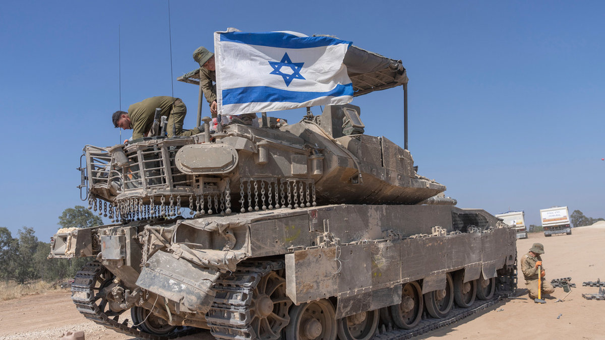 En israelisk soldat fäster en israelisk flagga på en stridsvagn nära gränsen till Gaza. Bild från den 15 april.