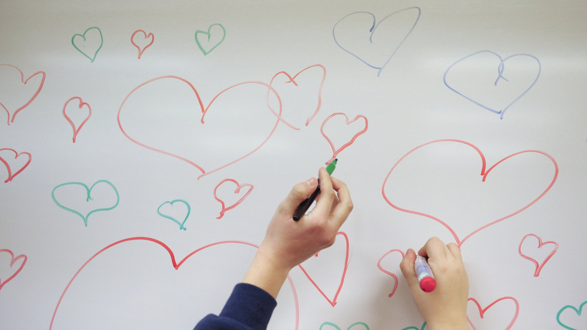 Personer ritar hjärtan på en tavla.