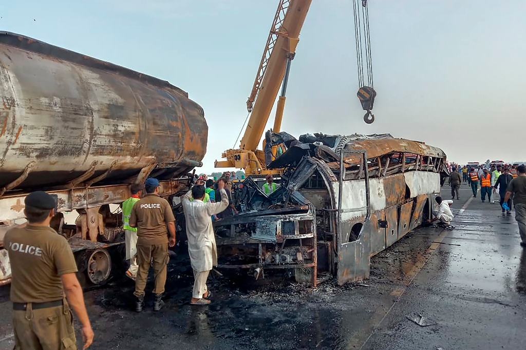 Polis och räddningstjänst arbetar vid olycksplatsen där en buss och en tankbil kolliderade i utkanten av staden Multan i Pakistan.