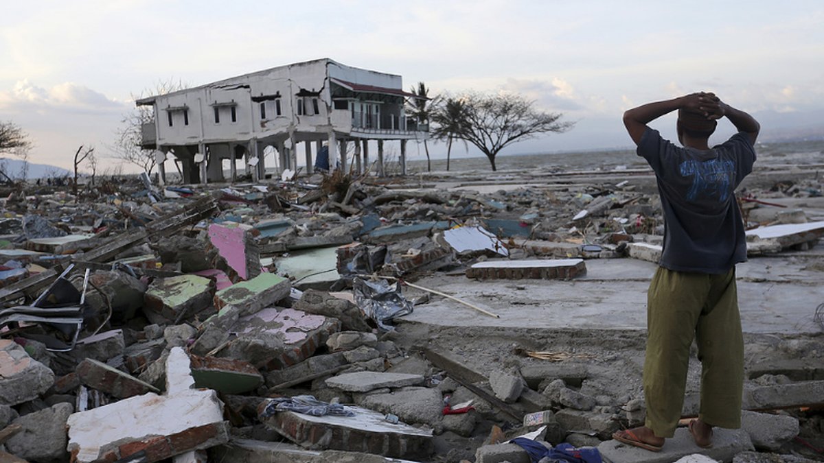 Pojke tittar ut över bråte efter tsunami.