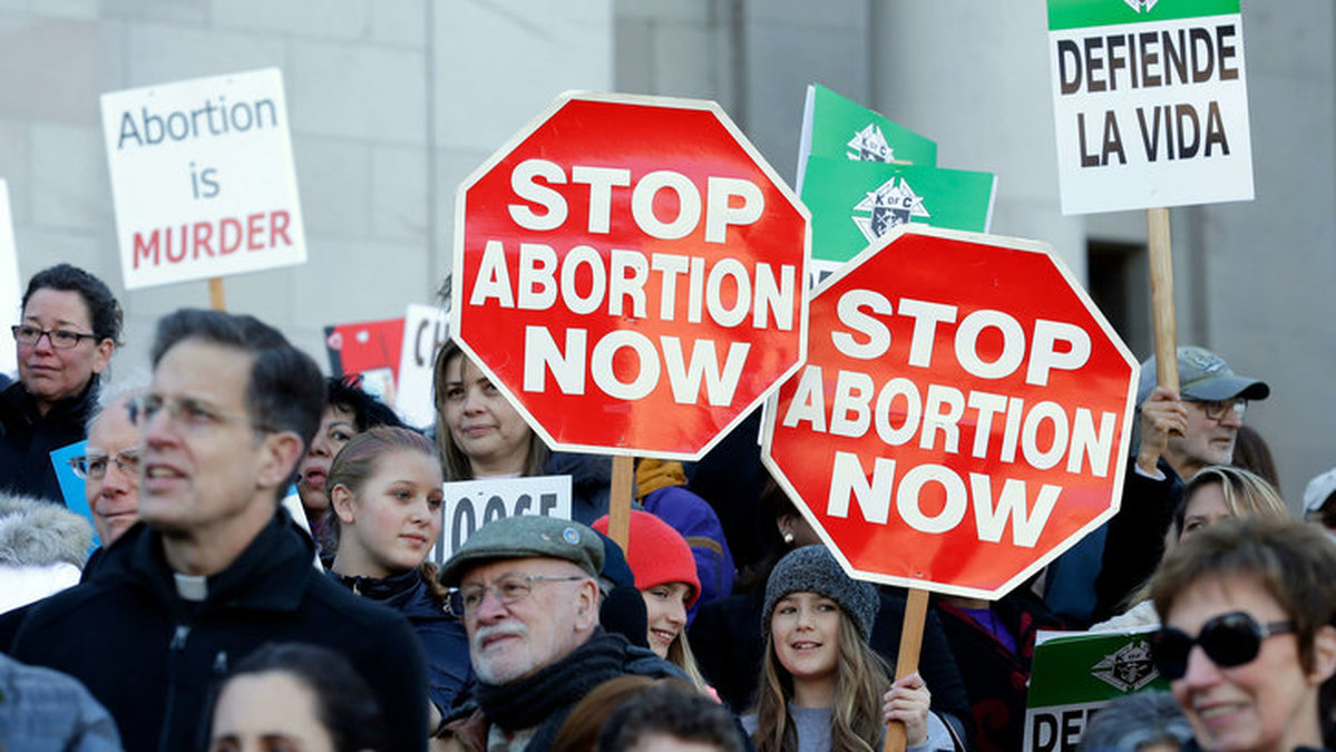 Abortmotståndare står samlade med plakat vid en demonstration.