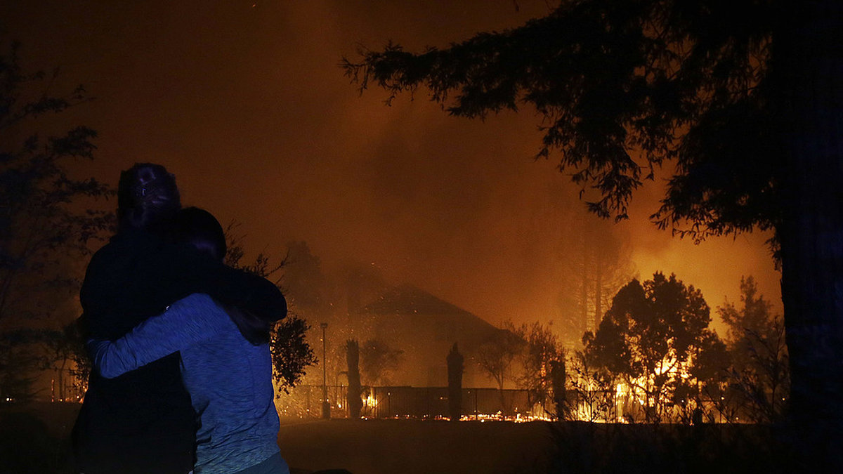 Två kvinnor kramas medan de tittar på deras hus som brinner ner i Santa Rosa. 