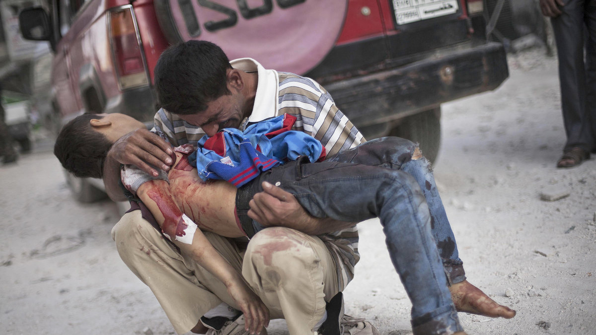 En man gråter när han håller sina döde son i sina armar efter en attack från syriska regimen i Aleppo. Oktober 2013.
