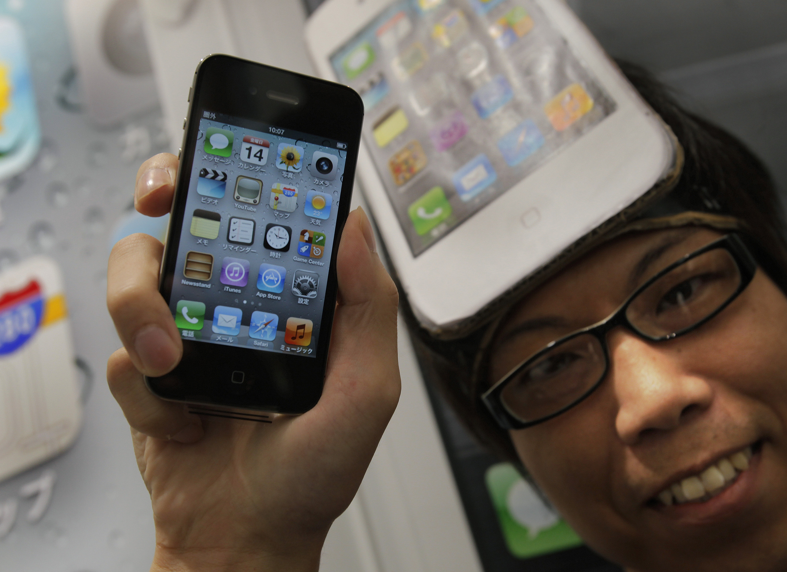 En japansk kund visar stolt upp sitt nya köp efter att iPhone 4S släppts på fredagen.