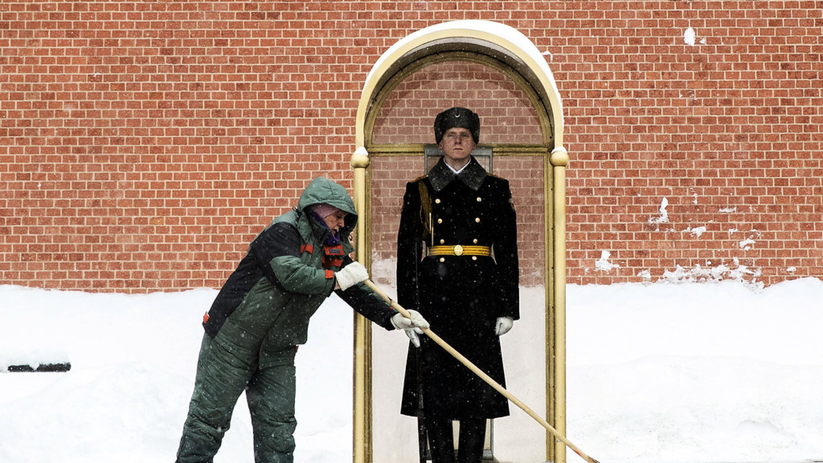 En man sopar bort snö framför en vakt vid Moskvamonumentet Den okände soldatens grav i februari 2021.