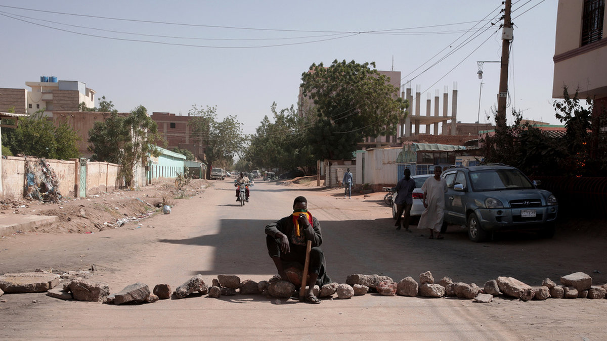 En man bevakar en av de uppbyggda barrikaderna i Sudan, här i Khartum på tisdagen.
