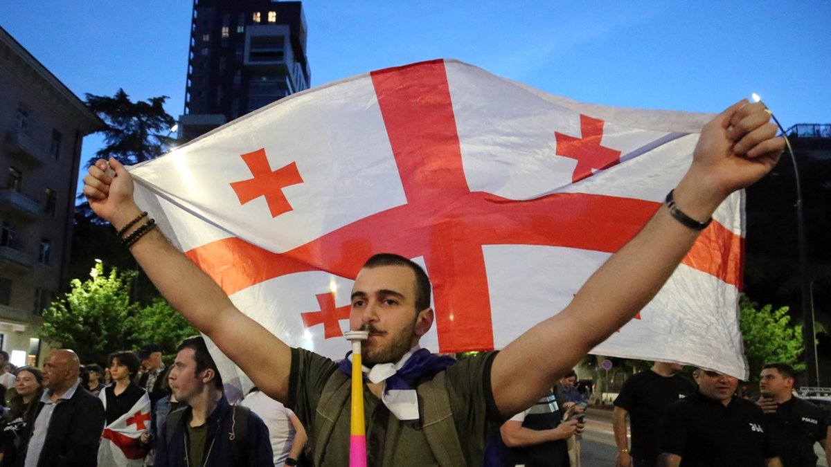 En demonstrant från oppositionen håller upp den georgiska flaggan när demonstrationerna fortsatte under måndagen.