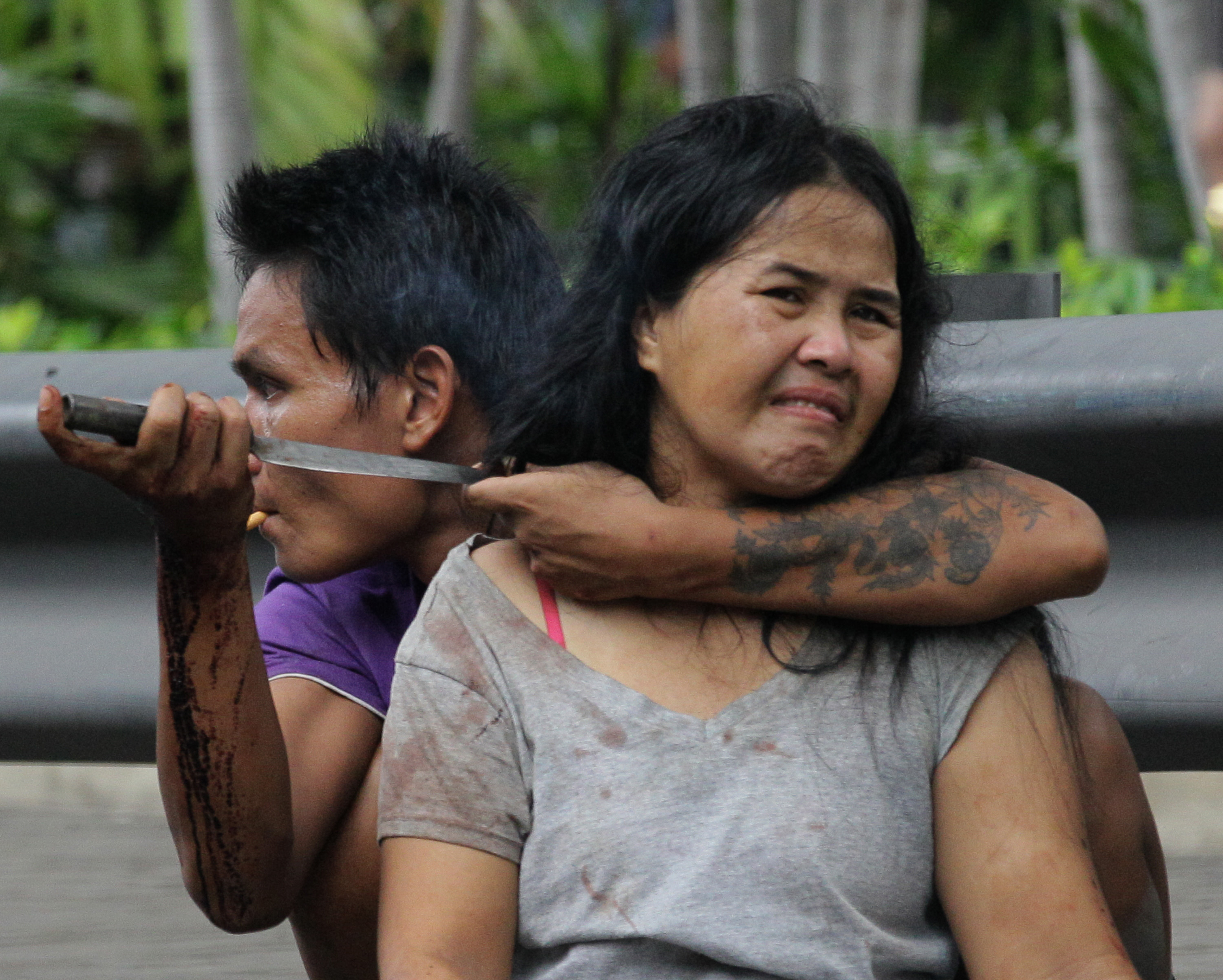30-årige Sakdawut Hamsiri, 
håller en kniv mot halsen på hans hustru Thawee Naiyanit 
på en gata i Bangkok.