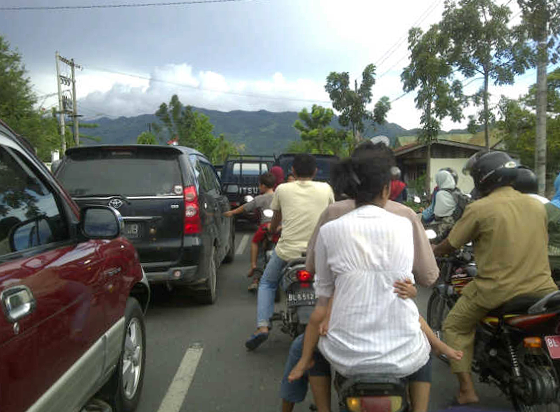Indonesiska invånare färdas på mopeder och i bilar för att fly undan en eventuell tsunami.