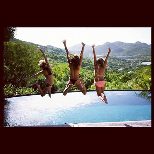 Tre glada tjejer tar ett dopp i en fräsch pool. 