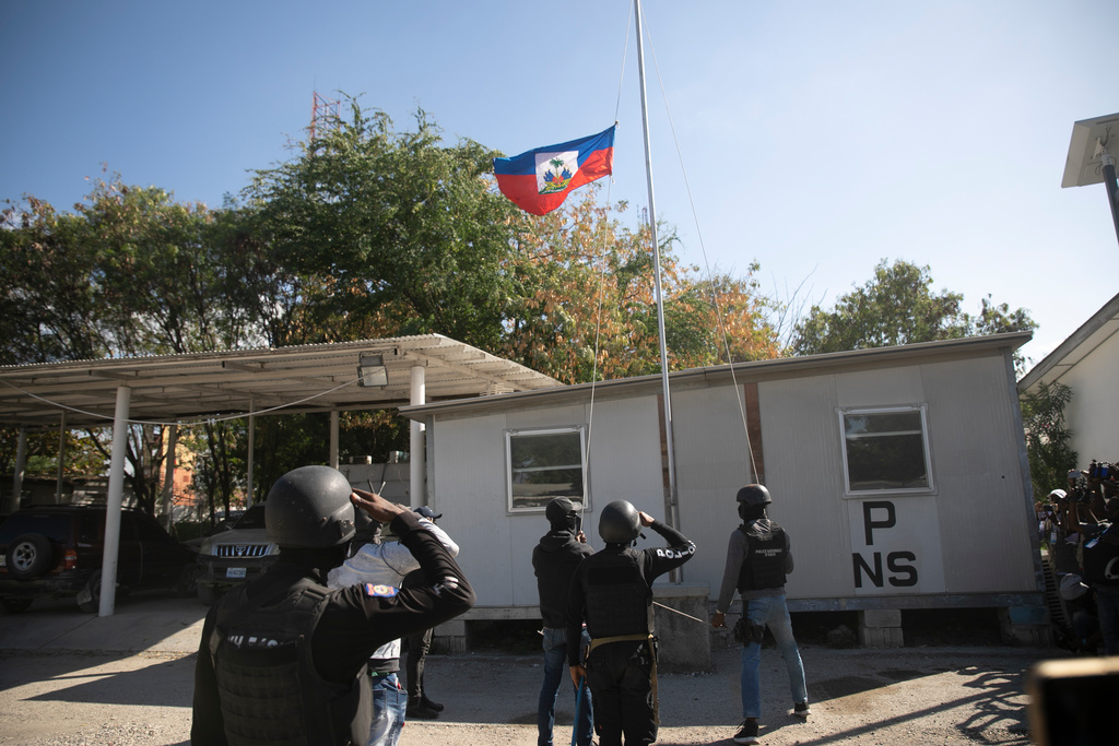 Poliser gör honnör vid Haitis flagga som halats på halv stång i Port-au-Prince.