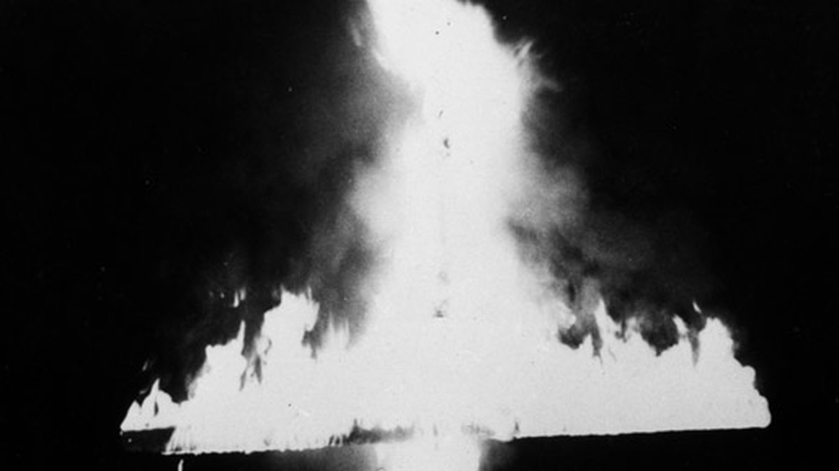 Ku Klux Klan-medlemmar kädda i vita kåpor står ett brinnande kors under en ceremono den 7 februari 1969. 