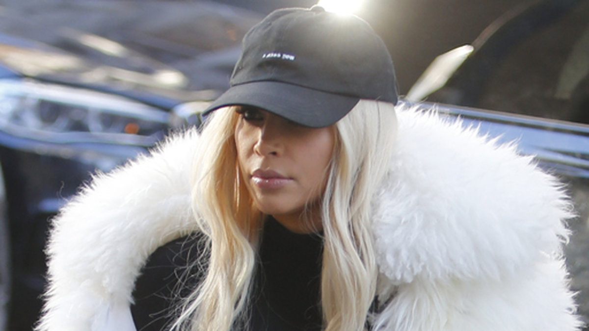 Kim Kardashian i blond peruk och vit päls.