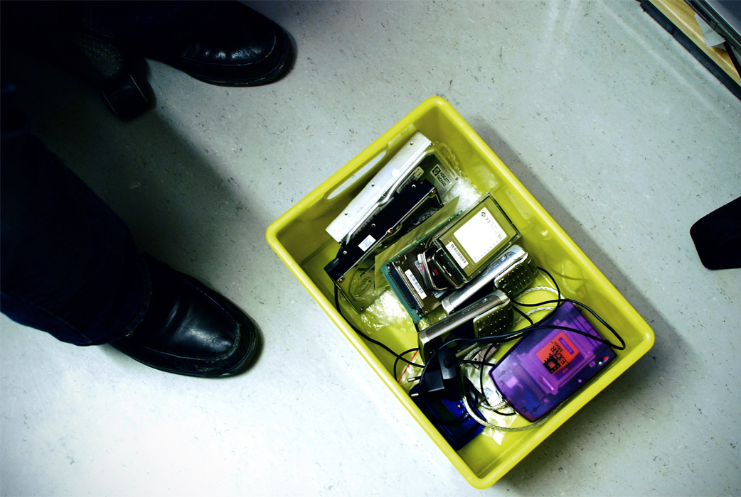 Beslagtagna tekniska prylar i gul låda.