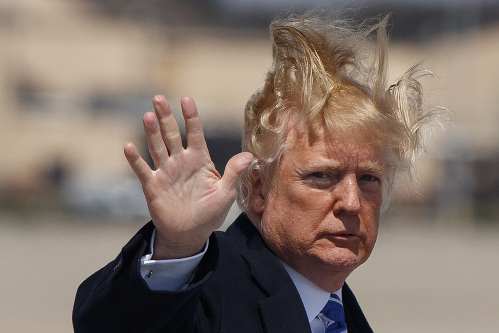 Donald Trump vinkar mot kameran med frisyren flygandes Donald Trump vinkar mot kameran med frisyren flygandes