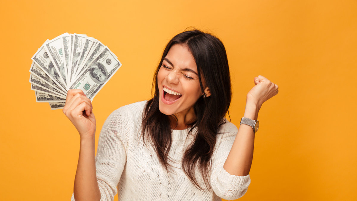 Kvinna håller i massvis av pengar och är glad 