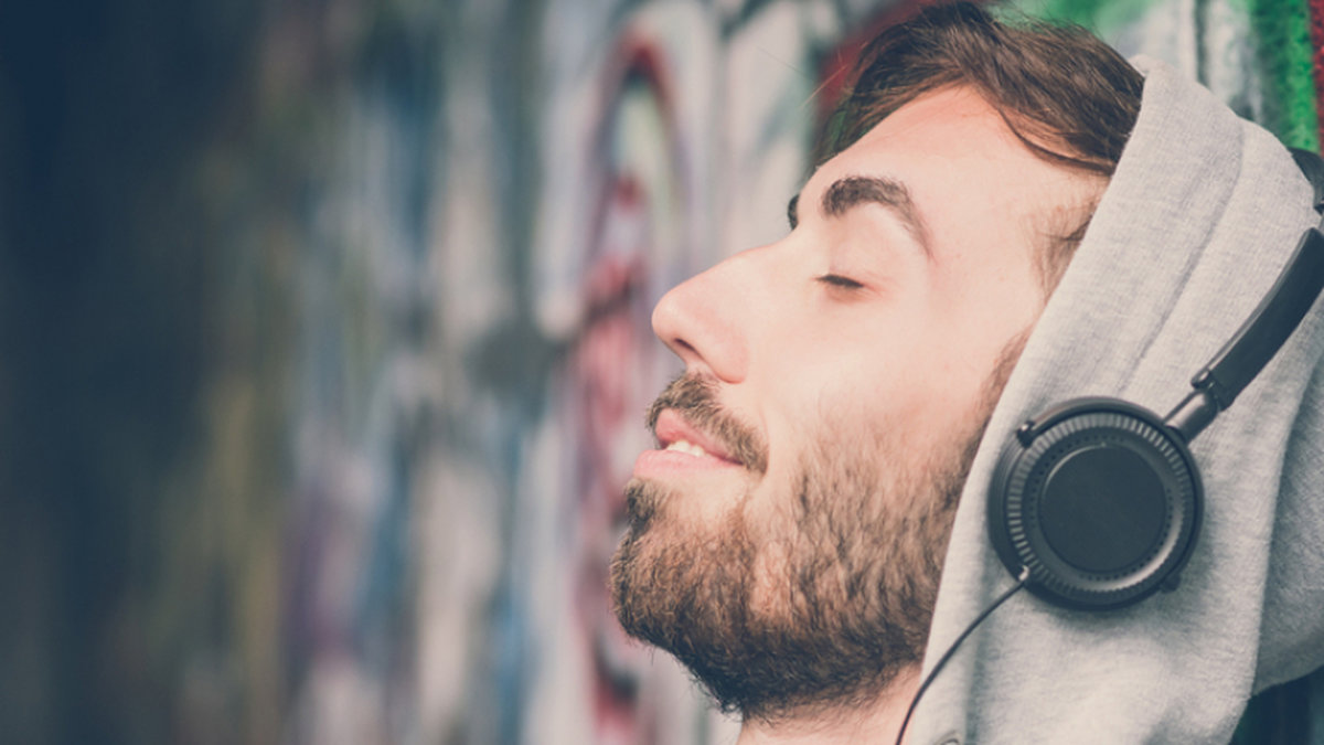 en man lyssnar på musik med högtalare vid en grå betongväg. 
