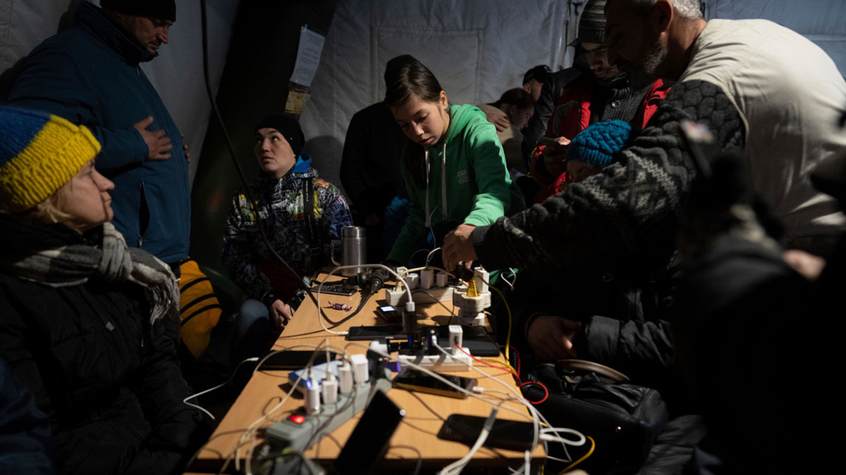Chersonbor laddar sina telefoner och värmer sig i ett av många tält som myndigheterna har rest.