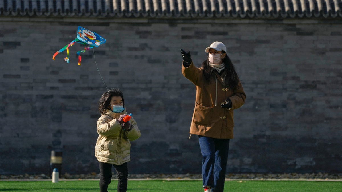 En kvinna och ett barn flyger drake i Peking under söndagen.