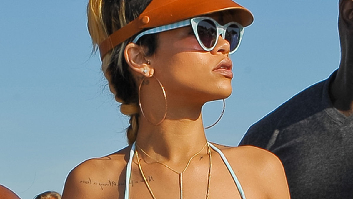 Rihanna visar sin tatuering på stranden. 