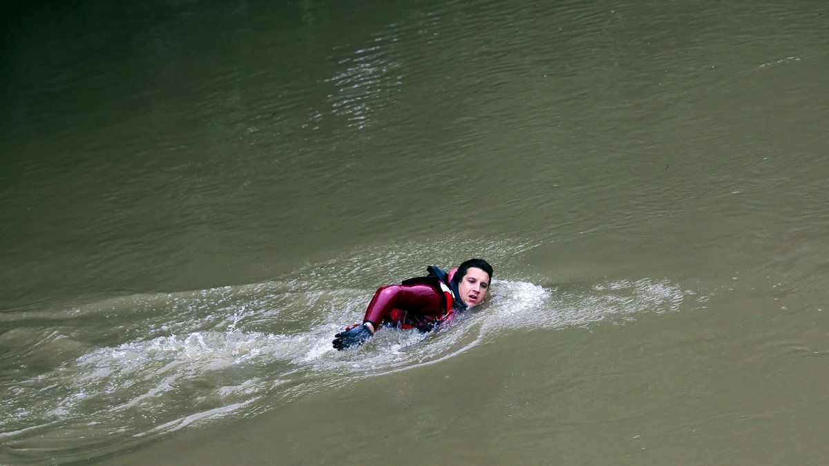 En brandman simmar i floden för att hjälpa till att surra fast båtar längst kajen i Paris.