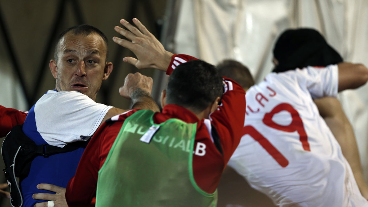 De albanska spelarna fick fly från planen. Här en supporter som attackerar dem på vägen ut. 