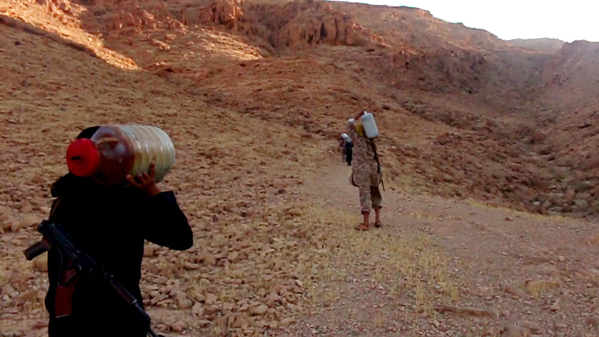 På bildena som släppts visas hur IS-terrorister bär bensintankar upp för kullen. 