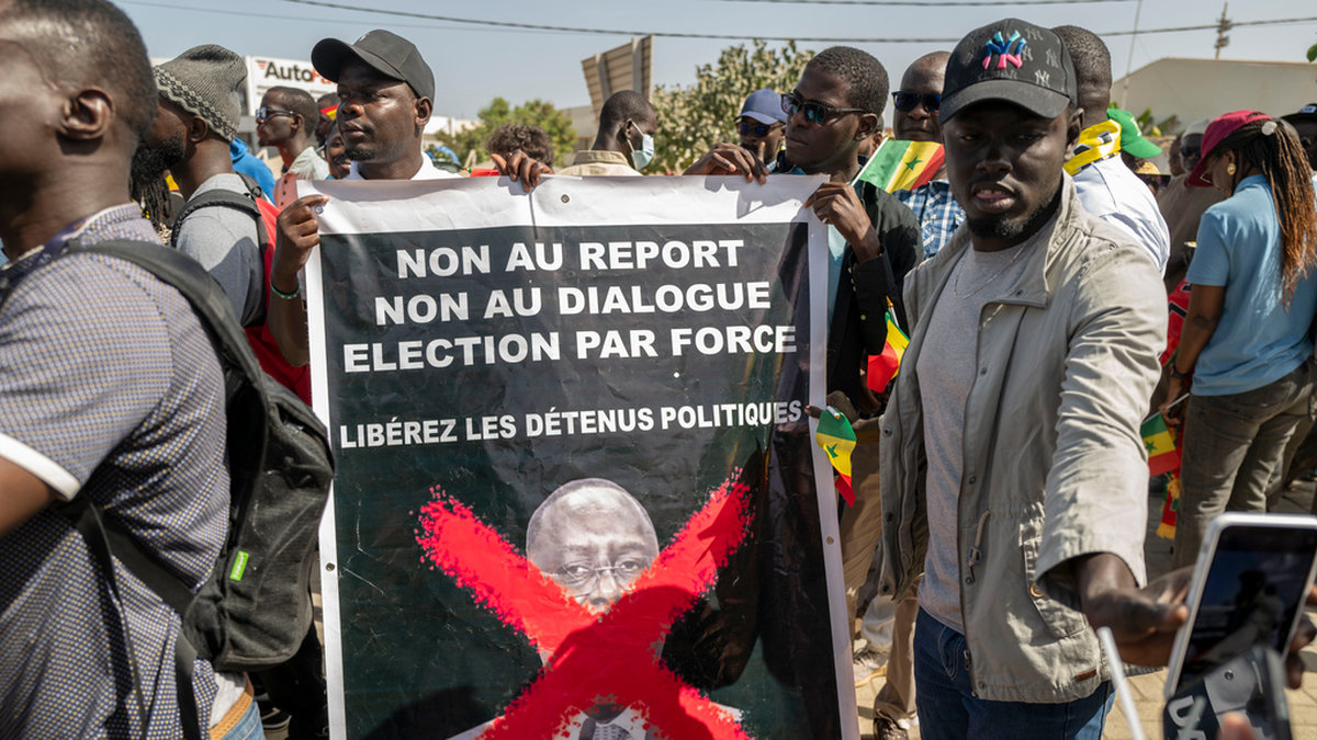Anhängare av oppositionen i Senegal protesterar på gator i Dakar med en skylt där det står 'Nej till fördröjning, nej till dialog, val med tvång'.