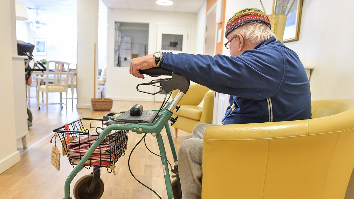 En äldre man med rollator sitter i en korridor på ett vård- och omsorgsboende. Arkivbild.