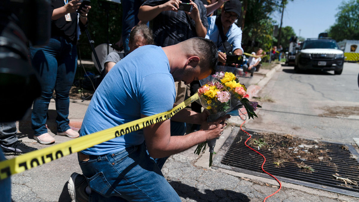 En sörjande man håller en bukett blommor vid polisavspärrningarna utanför Robb Elementary School i Uvalde, Texas.
