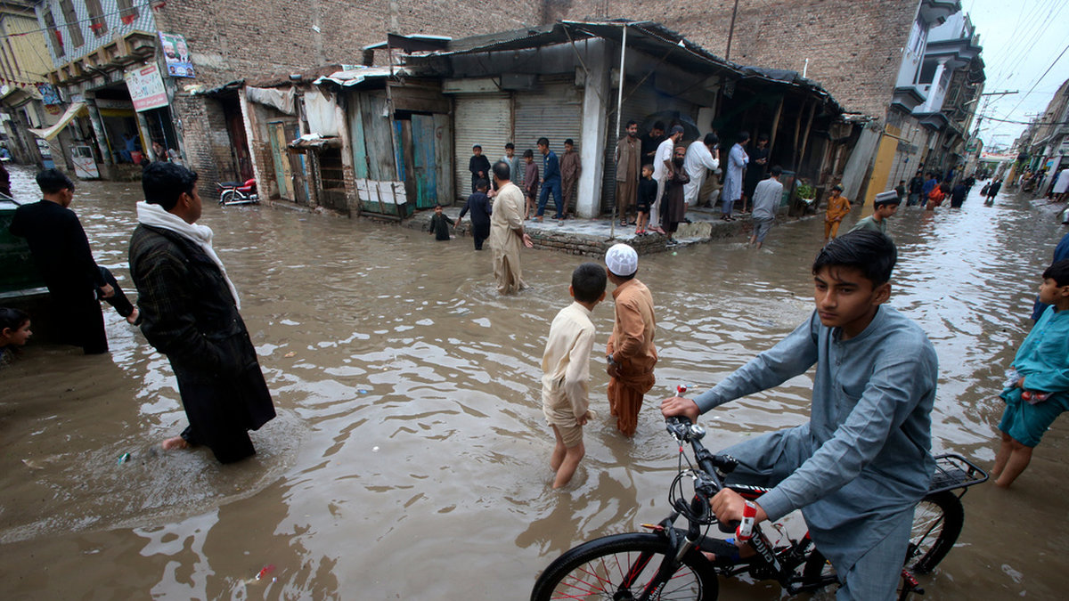 Människor vadar i vatten på en översvämmad gata i Peshawar i Pakistan tidigare i veckan.
