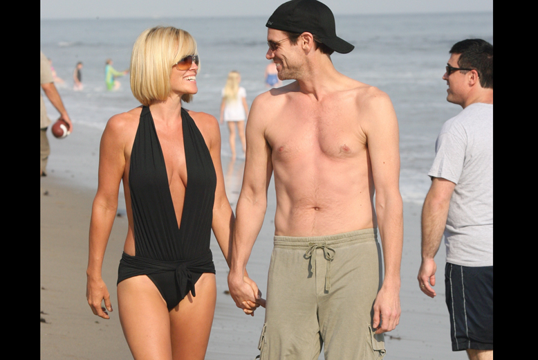 I tajt baddräkt med exet Jim Carrey i handen på stranden. 