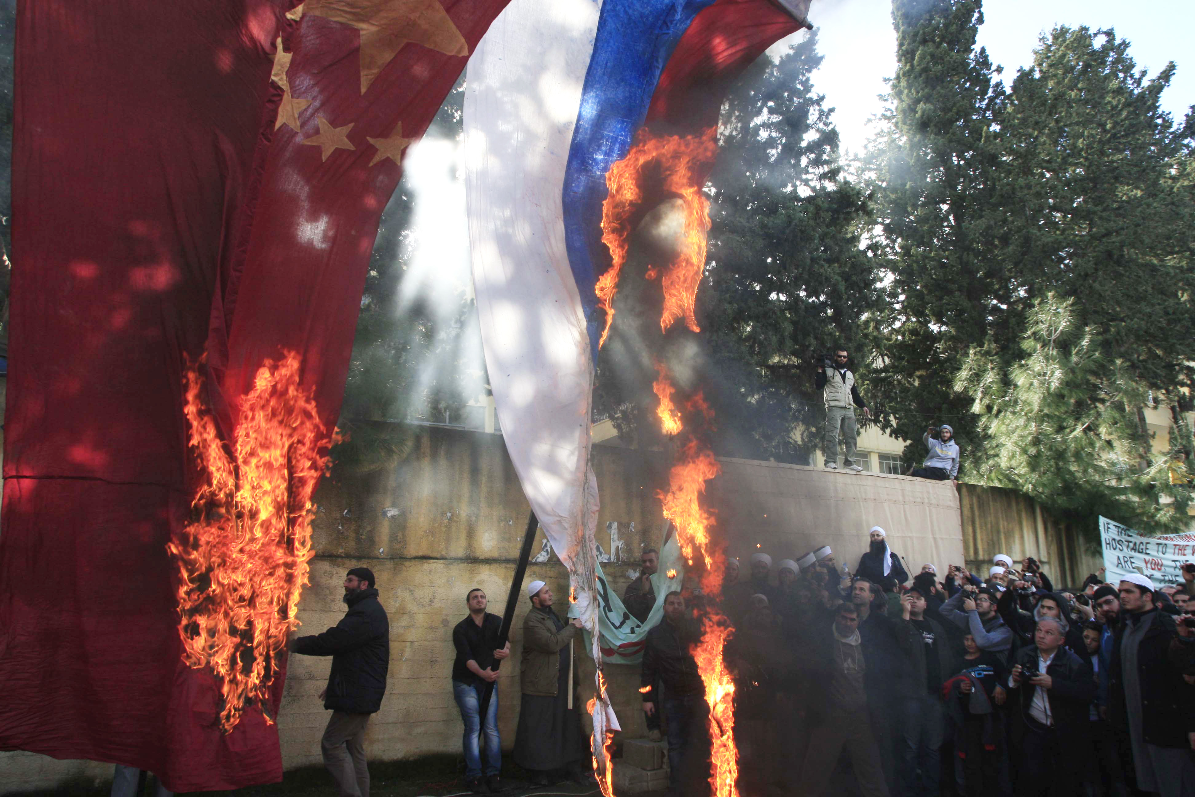 Anhängare av islamistiska grupper bränner Kina och Rysslands flaggor i protest.