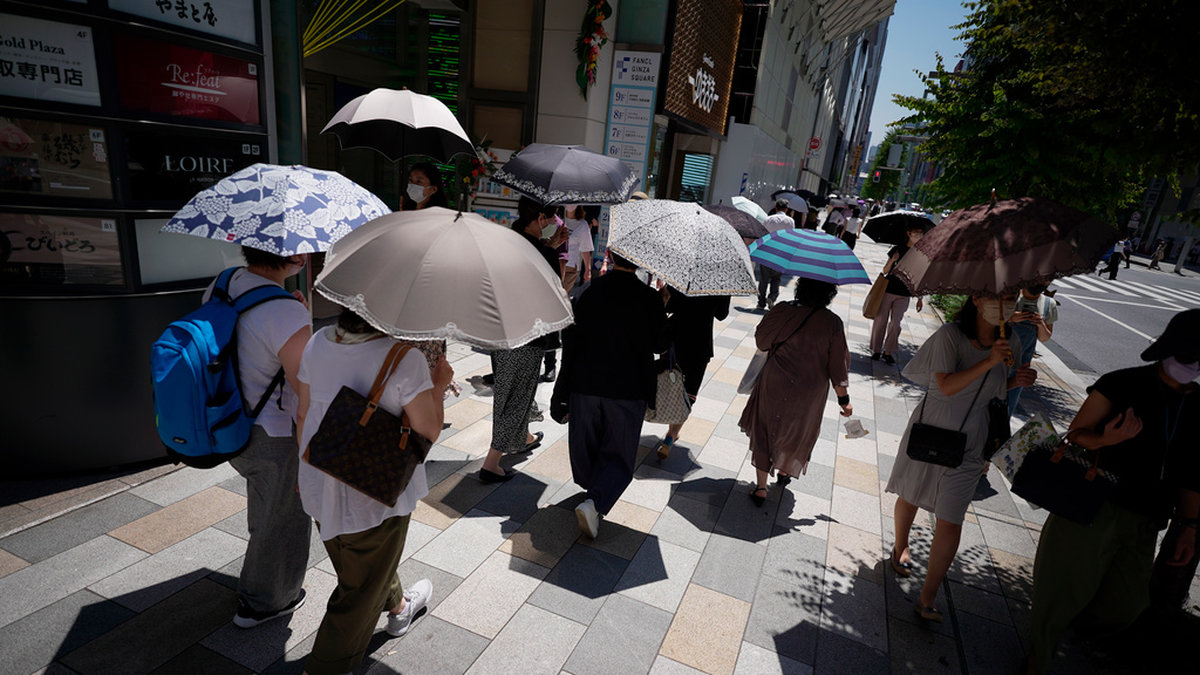 Människor tar skydd från solen under paraplyer i Tokyo den 28 juni. Arkivbild.