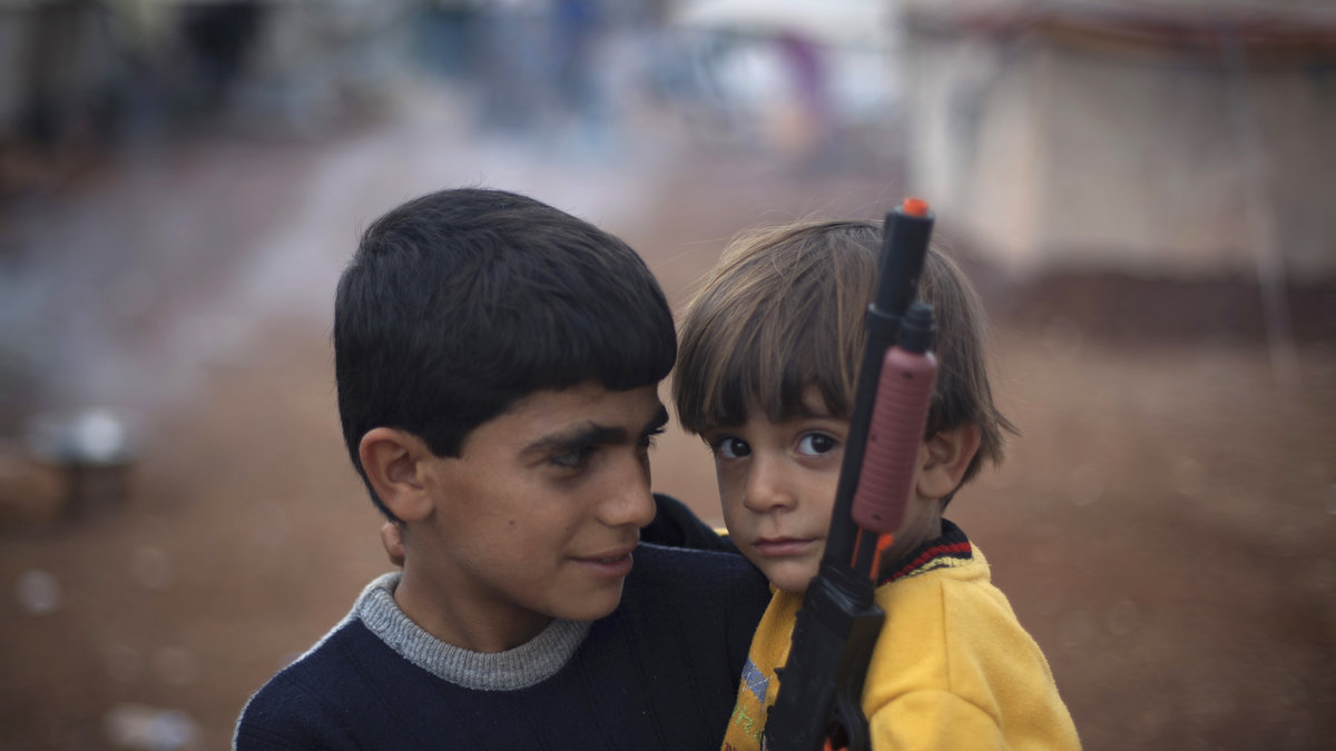 Två syriska pojkar som flytt med sina familjer leker med leksaksvapen i närheten av den turkiska gränsen.